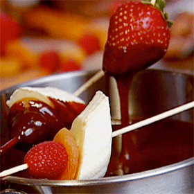 Chocolate fondue with pieces of fruit and cake